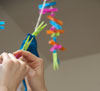 hands pegging white clothe with multi-coloured plastic pegs hanging in background