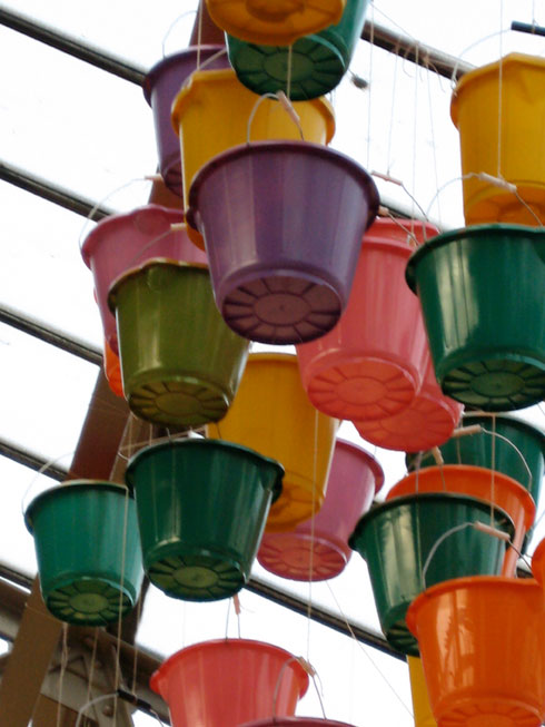 multicloured sprayed buckets hanging from glass ceiling of an old arm drill hall